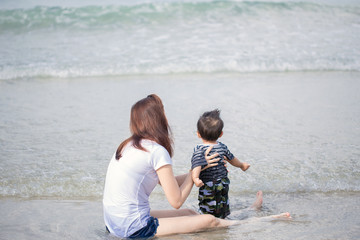 Mother and baby feet at the sea foam at the sunlight water is moving