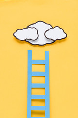 top view of paper ladder with clouds on yellow background, setting goals concept