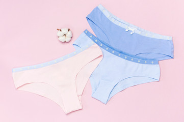 Female pastel cotton set panties and cotton flower on pink background top view flat lay with copy...
