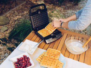 Preparation of homemade waffles in waffle irons outdoors in the garden