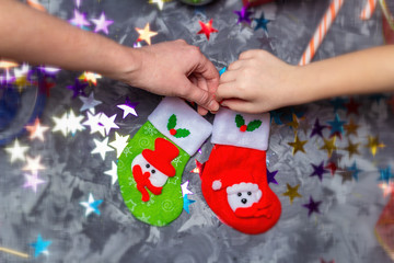 Mom and child are preparing decorations, are holding Christmas socks for gifts. Hands close up. View from above. Flat lay