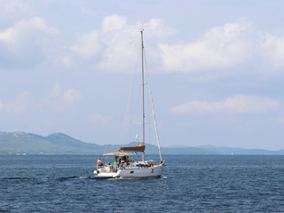 Fototapeta premium A sailing yacht is anchored in a bay. People bathe in the sea. Active rest on the Adriatic Sea of the Mediterranean region. Dalmatian riviera of Croatia. Prestigious and rich lifestyle