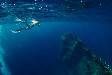 Fototapeta premium Free diver man swimming in sea near shipwreck in Bali