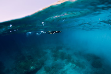 Freediver in wetsuit swimming in the ocean, underwater view