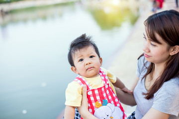Portrait of a crying little boy who is being held by her mother