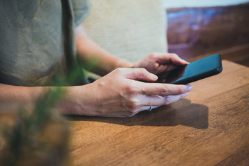 woman holding a smartphone looking down the screen in restaurant.