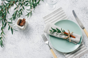 Elegant table setting with linen napkin, sprig and cinnamon on white background