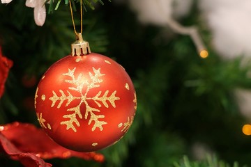 Christmas decoration tree. Red bauble and golden gift box hanging from Christmas tree.