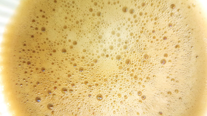 Bubbles of hot coffee close up in white glass.