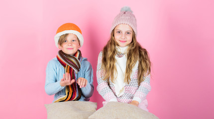 Stay warm and comfortable. Warm up your winter wear with cute and cozy accessories. Siblings wear winter warm hats sit on pink background. Children boy and girl warm up with pillows and hats