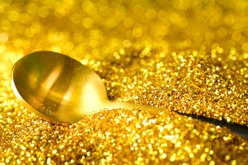 Golden spoon on glitter gold dust background ,Luxury and elegant concept