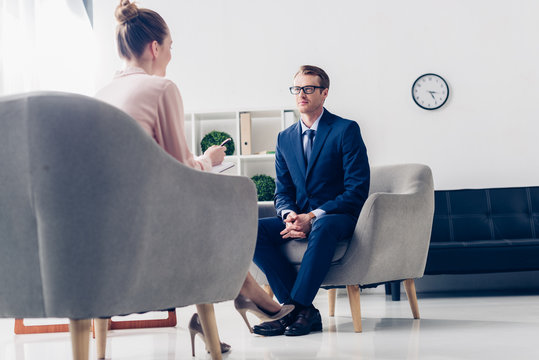 low angle view of handsome businessman giving interview to journalist in office