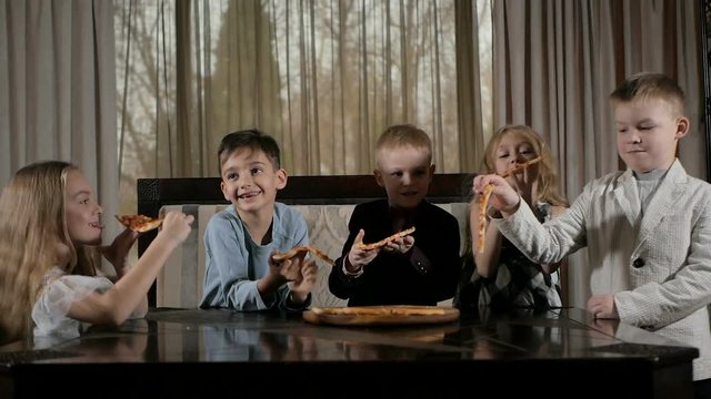 Happy kids eat pizza in the restaurant