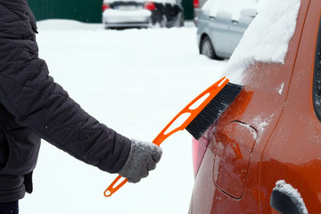 Man brushing and shoveling snow off car after snow storm. Brush in mans hand. Winter, snow, vehicle.