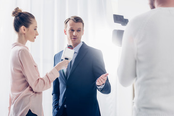 cheerful handsome businessman giving video interview to journalist and gesturing in office