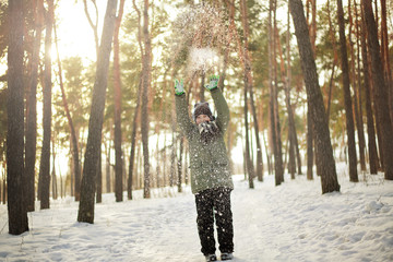 child playing with snow in the winter forest
