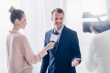 smiling handsome businessman giving video interview to journalist in office