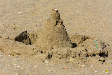 Sandy castle built by children with wet sand on the beach. Castles on the sand. Fun in the sand on the beach on a sunny day. Concept of summer vacation and travel.