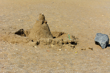 Sandy castle built by children with wet sand on the beach. Castles on the sand. Fun in the sand on the beach on a sunny day. Concept of summer vacation and travel.