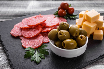 delicious sliced salami on a stone plate wooden background