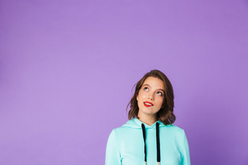 Thoughtful young woman posing isolated over purple background wall.