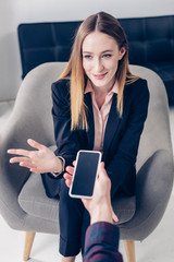 high angle view of cheerful businesswoman in suit giving interview to journalist in office