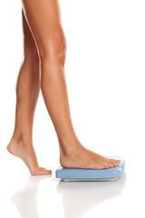Young woman standing on a scale on white background