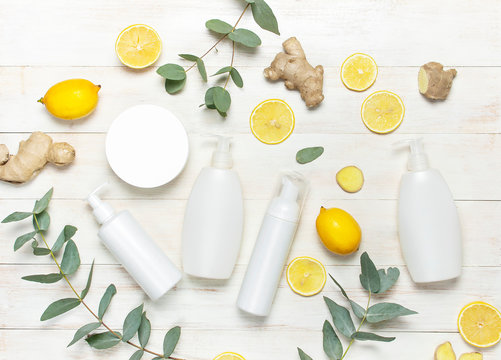 Whites Cosmetic bottle containers, fresh lemon, ginger root, eucalyptus on white wooden background top view flat lay copy space. Blank label for branding mock-up. Natural beauty product concept