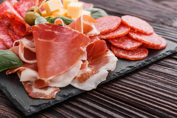 Cold smoked meat plate on a rustic wooden background