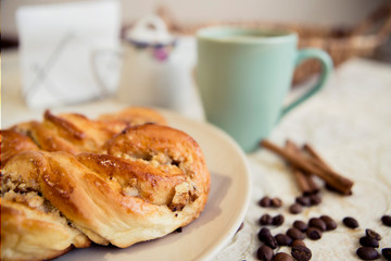 Buns, cup of coffee, cinnamon sticks and coffee grains on the table.