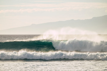 Wonderful nature show with power waves breaking on the shore with energy - perfect for surf activity and water sports. Tropical island on the background for vacation and leisure concept