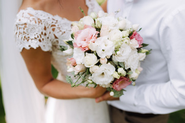 Obraz na płótnie Canvas bride holding bouquet of flowers in rustic style, wedding bouquet Groom hugs bride