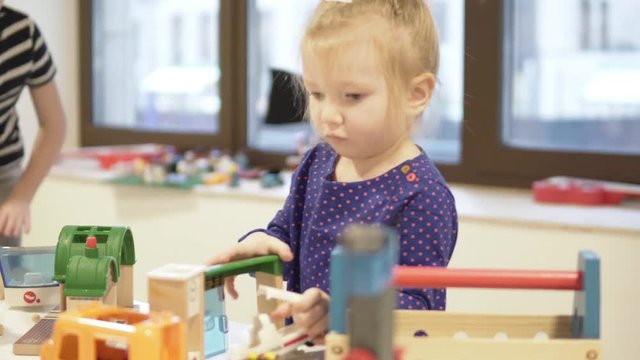 A little girl and her older brother are playing educational toys in the children's room. Children are passionate about the process of assembling a constructor