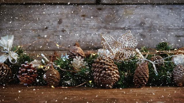 Video composition with falling snow over desk with many pine cones