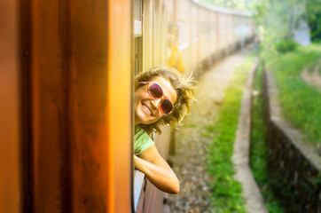 Young woman enjoying traveling by train through Sri Lanka 