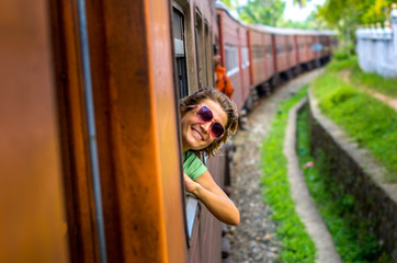 Young woman enjoying traveling by train through Sri Lanka 