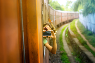 Young woman enjoying traveling by train through Sri Lanka 