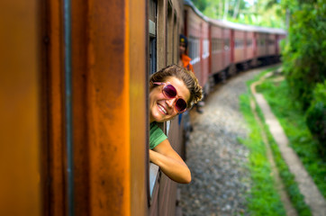 Young woman enjoying traveling by train through Sri Lanka 