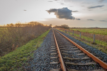 Fototapeta na wymiar Apparently endless long single rail tracks at sunset