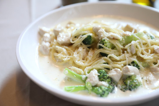 alfredo spaghetti broccoli chicken white sauce in restaurant background