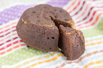 Chocolate cake on white plate on colorful kitchen towel, tasty sweet dark brown biscuit