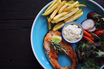Roasted salmon steak , baked salmon with salad fresh vegetable pm wooden table