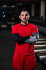 Handsome man with big muscles, posing at the camera in the gym