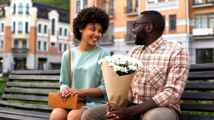 Beautiful young woman meeting boyfriend on first date, man presenting flowers - obrazy, fototapety, plakaty