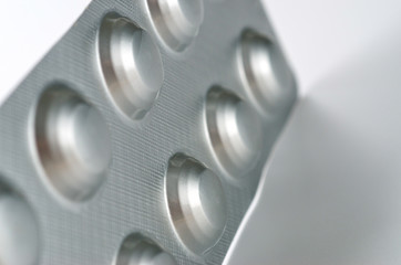 Plate with round medical pills silver color close-up shot