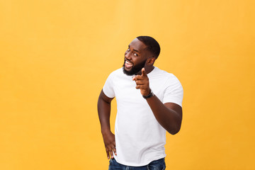 Funny young African customer smiling happily and pointing his index fingers at camera as if choosing you and inviting to big sale. Positive emotions, facial expressions, feelings. Selective focus.