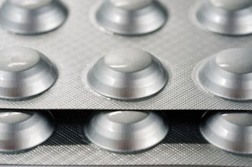 Plate with round medical pills silver color close-up shot