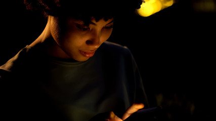 American girl texting message in smartphone outside night club, ordering taxi