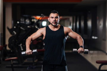 Fototapeta na wymiar Bodybuilder doing Exercise for the shoulder muscles, deltoid with dumbbell in the gym