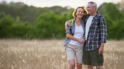Carefree retired Caucasian American couple enjoying leisure hiking in the wilderness outdoors 